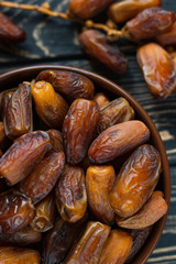 Sweet dessert dried date in brown ceramic bowl on an old dark wooden table. Low key, selective focus. Delicious ingredient for vegan dessert. Close up