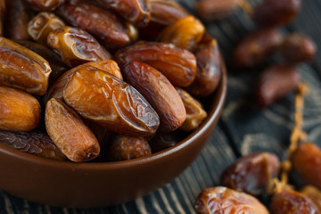 Sweet dessert dried date in brown ceramic bowl on an old dark wooden table. Low key, selective focus. Delicious ingredient for vegan dessert. Close up