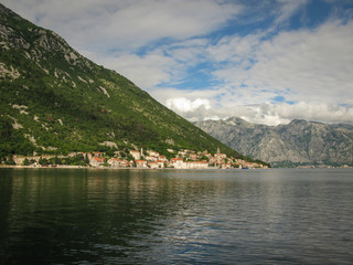 Fototapeta na wymiar panoramic view from the ship to Perast, Kotor bay and the surrounding mountains, blue sky with white clouds, Montenegro