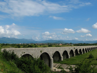 Fototapeta na wymiar Tsar's bridge over Zeta river in Niksic on a sunny day, mountains, blue sky, Montenegro