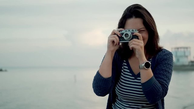 young woman takes photos on a retro camera outdoors.