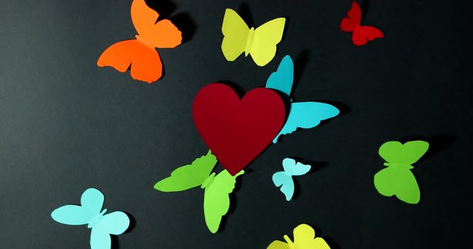 Stop motion red heart and multi-colored butterflies on a dark background Valentine's Day holiday.