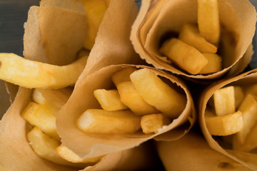 Fast food. French fries in parchment paper. Macro. Studio light