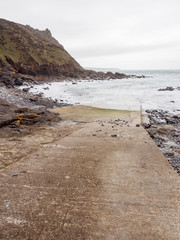 Wide vertical view of a concrete boat ramp along the beach of Priest's Cove on a cloudy day. Cape Cornwall, United Kingdom. Nature and fishing. - 312219690