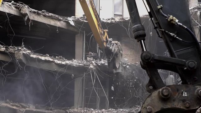Chicago,IL/USA-August 10th 2019: slow motion footage of a mechanical bulldozer destroying a building architecture in downtown area. the industrial machine equipment dismantles concrete at the site 