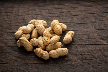 Roasted peanuts scattered on rustic, dark wood background