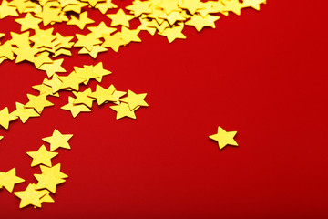 Gold stars on red background. The concept of greeting cards, headlines and web site. A scattering of Golden stars