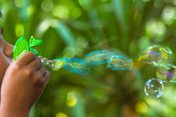 child blowing soap bubbles in the park