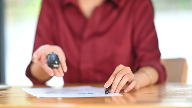 Young woman together with the car purchase agreement and keys.