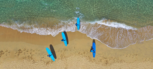 Fototapeta na wymiar Aerial drone ultra wide photo of surfers practising with their surf boards in tropical exotic sandy bay with turquoise sea