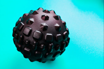 Black bumpy foam massage ball is a rubber ball on a blue background.
