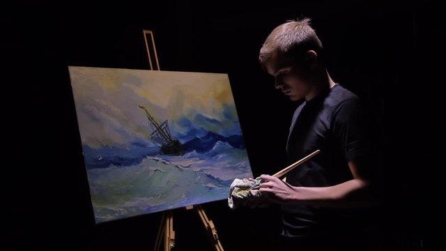 Artist copyist paint seascape with ship in ocean. Craftsman decorator draw as boat sail on blue sea with acrylic oil color. Draw finger, brush, knife palette. Canvas, easel in studio, indoor.