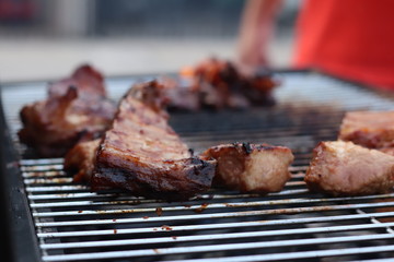 Assorted delicious grilled meat with beef stick and beef steak on black stove with smoke. grills some kind of marinated meat and vegetable on gas grill during summer party time. 