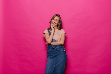 Beautiful serious young woman is thinking and thoughtful on isolated pink background. Charismatic girl is showing concept of emotions in professional studio.