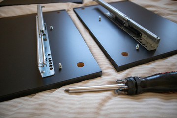 Process of assambling a black drawer of a furniture from sorting pieces to screwing them