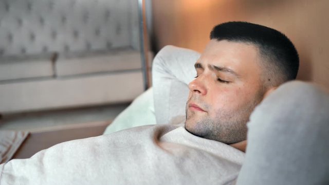 Closeup tired Caucasian man lie on bed with closed eyes trying to sleeping on softness pillow