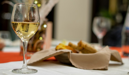 elegant table setting in background with a glass of white wine on close-up