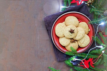 Homemade sugar cookies with cardamom in the New Year and Christmas style on the red clay plate on a brown background concrete. Copyspace.