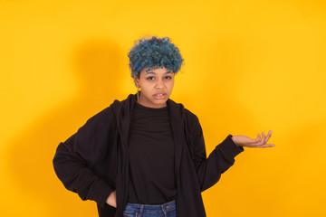 young african american girl or woman isolated on yellow background with expression and blue hair