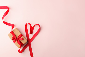 Present or gift box, satin red ribbon heart on pink background top view. Valentines day greeting...