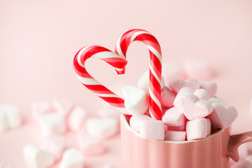 Mug with candy and marshmallow hearts on pink background. Romantic, St Valentines Day concept,...
