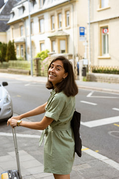 Young woman walks with a suitcase in the streets of Luxembourg. Summer vacation trip.