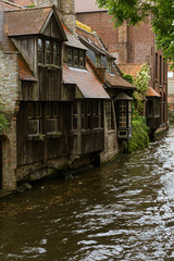Fototapeta na wymiar Bruges, Belgium. Medieval ancient houses made of old bricks at water channel in old town. Summer day with sunlight and green trees. Picturesque landscape.