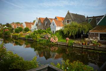 Fototapeta na wymiar Beautiful and picturesque landscape of the village of Edam, the Netherlands. Typical dutch houses in front of a canal, riverside with trees and flowers. Spring outdoors.