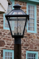 This old fashioned street lamp is in front of the stone house.