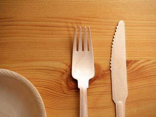 Modern simple wooden bowl, fork and knife, top view, on wooden table. Concept ecology and recycle solution.