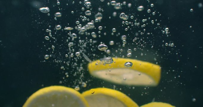 Lemon splashing into water on black background closeup in super slow motion.