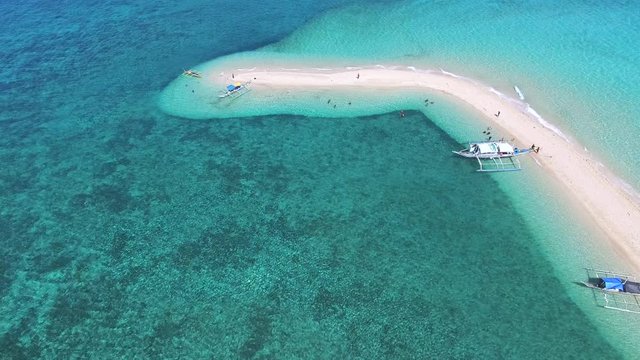 Tilt and push towards groups of tourist day trippers docked on an elbow skinny temporary sandbank formed by ocean currents moving sand and silt