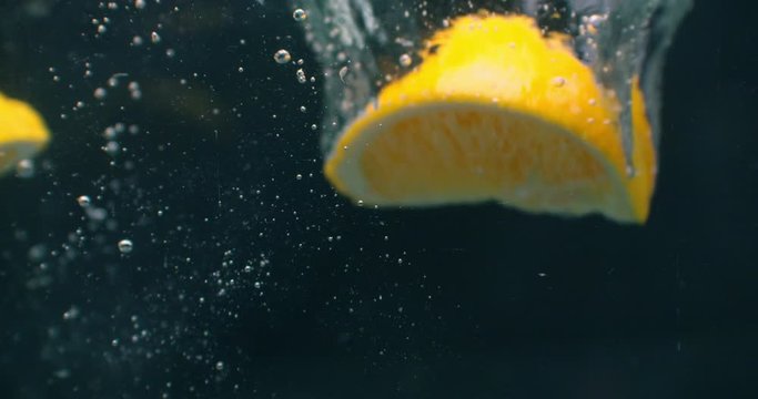 Lemon splashing into water on black background closeup in super slow motion.