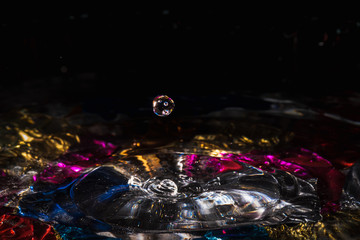 water drops splash forming ripples and waves and abstract water columns in a colorful background