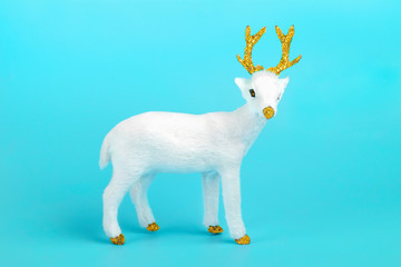 Fototapeta premium white deer decorated with sequin in golden color on blue background. Happy New Year, Merry Christmas concept Holiday card Flat lay Top view Scandinavian style Place for text