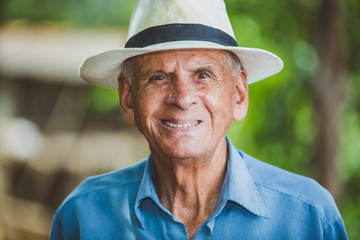 Portrait of smiling beautiful older male farmer. Elderly man at farm in summer day. Gardening...