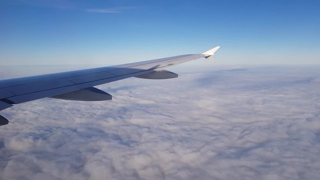 Fliegender Ausblick aus Flugzeugfenster rechts mit Flügel oberhalb geschlossener Wolken