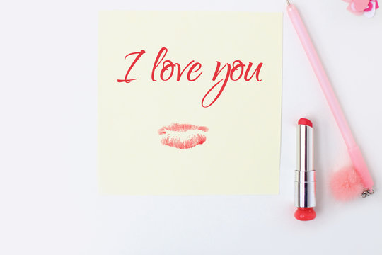 Flat lay: yellow paper, pink pen, pompom, lipstick, confetti hearts, lip print, i love you text. Making postcard in envelope for Valentine's Day.Do it yourself.Photo from the series