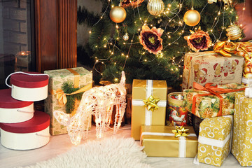 Golden Christmas gifts and deer near Christmas fir-tree taken cl