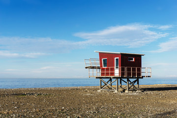 Lifeguard tower on empty beach. Blue sky sea shore sunset landscape. Lack of tourists during low winter season.