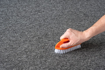 man hand without gloves cleaning gray  carpet with brush and microfibre cloth. dry cleaning technique - 312245674