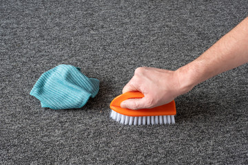 man hand without gloves cleaning gray  carpet with brush and microfibre cloth. dry cleaning technique - 312245694