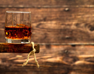 Whiskey with ice or brandy in a glass and a square carafe on an old wooden background. Whiskey with ice in a glass. Whiskey or cognac. Selective focus.