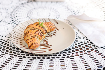 Chocolate croissant on the table in a cozy chocolate bar. Tasty and easy food.