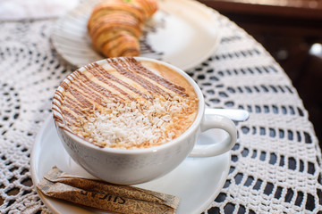 Chocolate croissant with coffee and coconut powder. Tasty and fresh food.