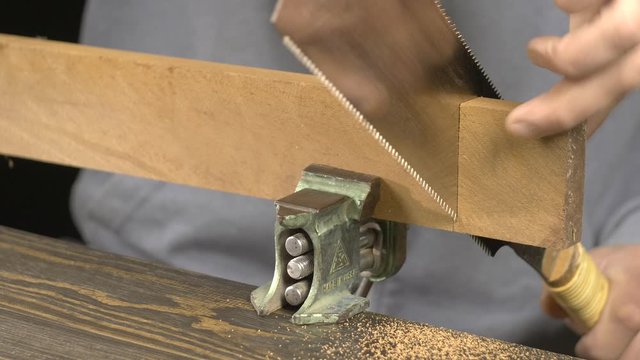 a carpenter saws a blank for a wooden comb with a Japanese saw