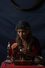 Gypsy fortuneteller or esoteric Oracle holding a smoking piece of wood and a magic crystal ball