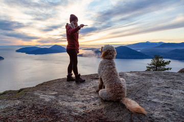 Adventurous Girl Hiking on top of a Mountain with a dog during a colorful sunset. Taken on Tunnel...