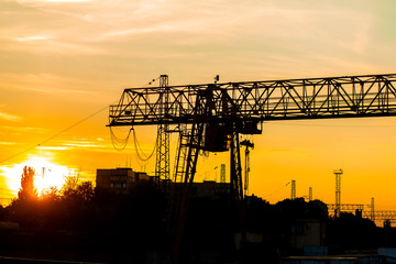 overhead crane at the railway station. Crane silhouette on sunset background. Heavy industry concept.