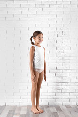 Cute little girl in underwear near white brick wall